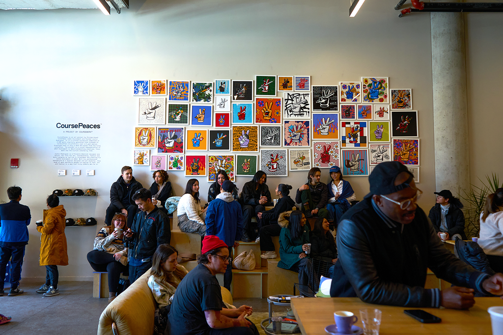 Drip Collective wall of CoursePeace framed prints and customers sitting beneath it